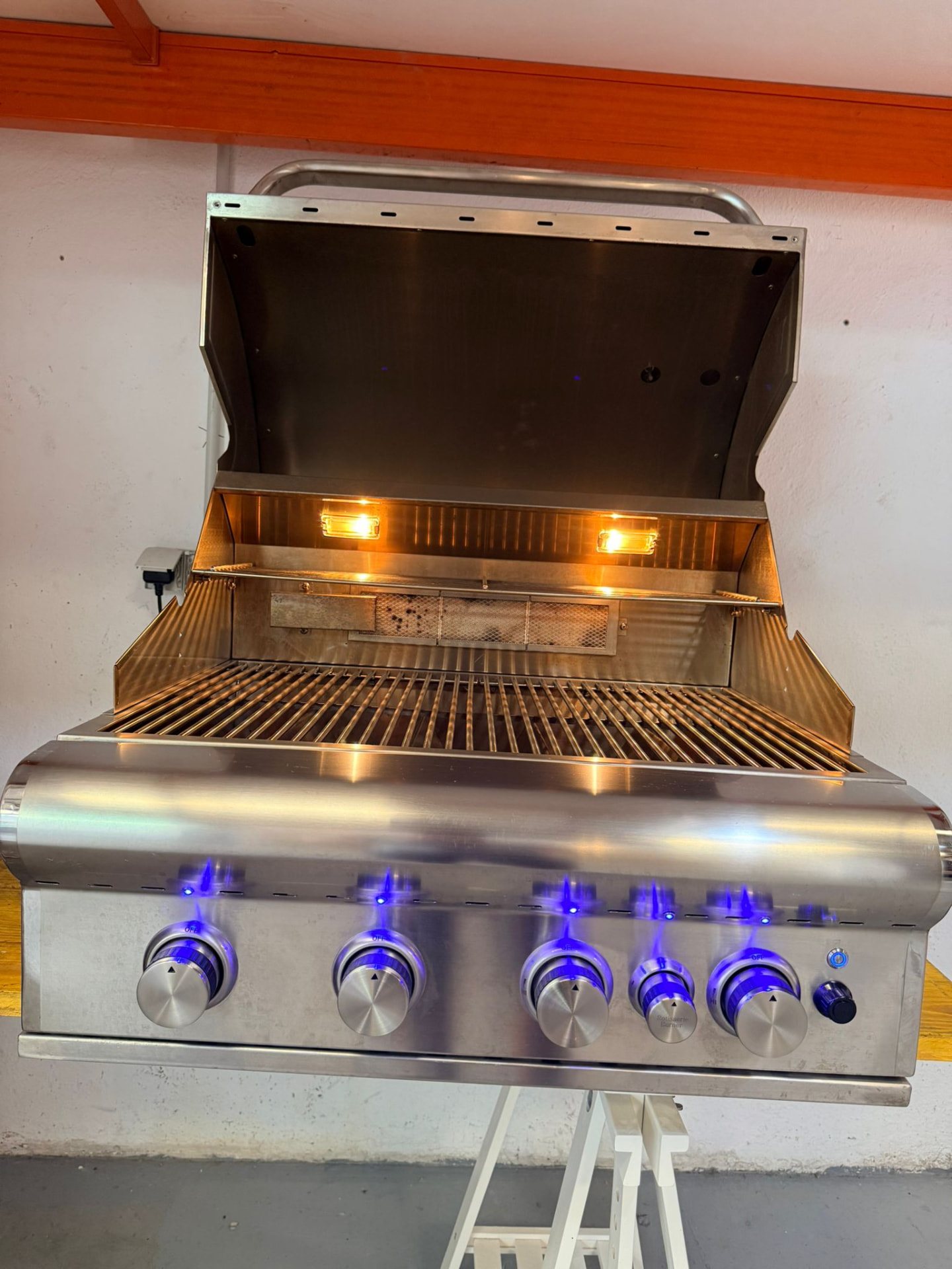 Åpen grill med rister, innvendige lys tent og blåbelyste brytere.